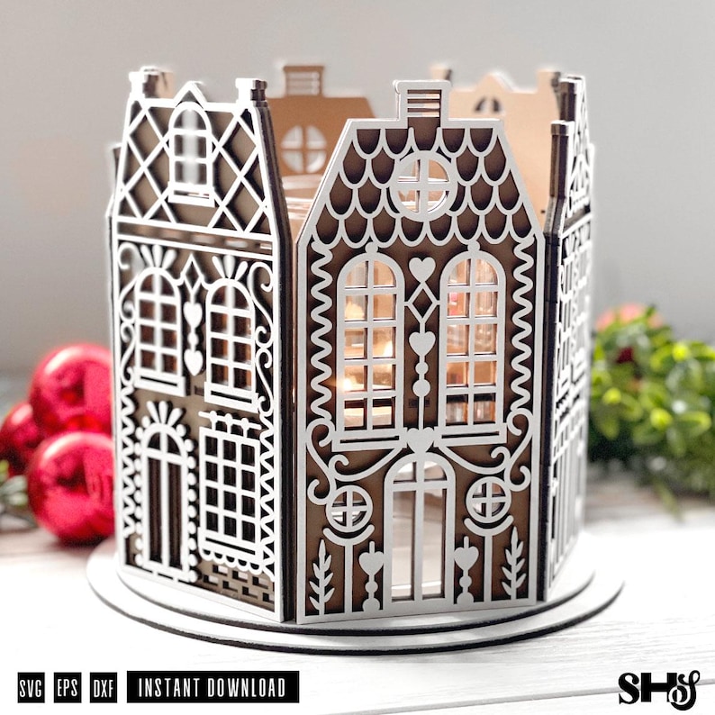 May include: A brown and white laser-cut gingerbread house lantern featuring intricate architectural details, arched windows, heart-shaped accents, and a scalloped roof design. The structure is circular, crafted from layered panels with cutouts.