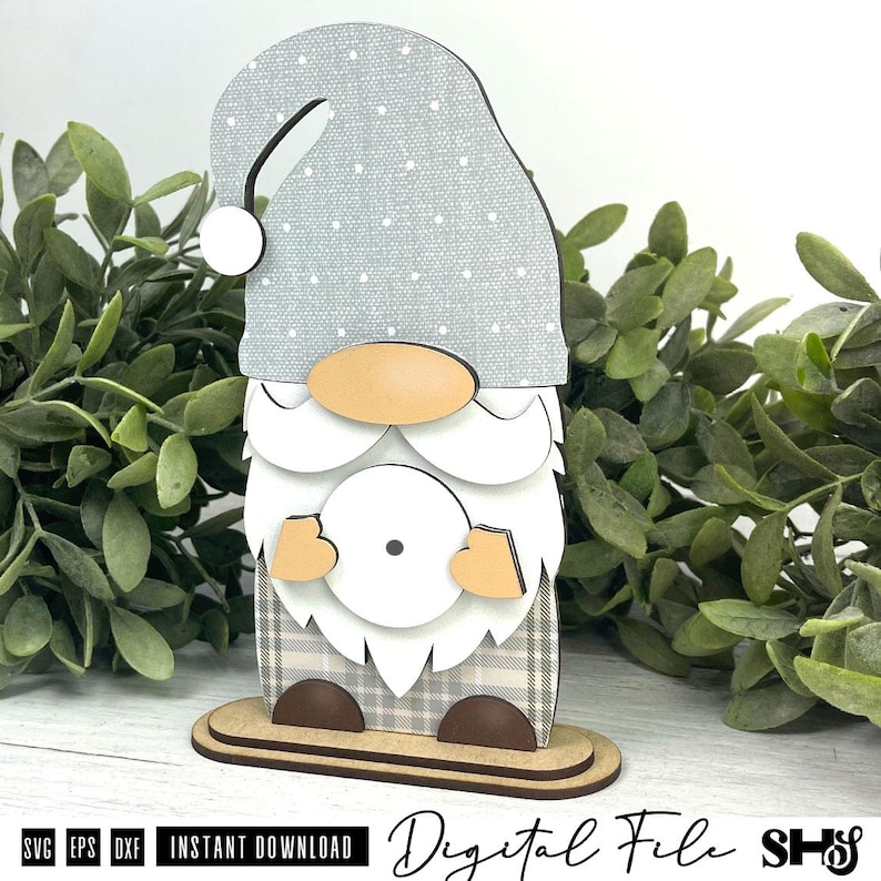 May include: A layered gnome cutout featuring a grey hat with white polka dots, a tan nose, a white beard, and a plaid patterned body. The gnome stands on a two-tiered base and includes the text SVG, EPS, DXF, INSTANT DOWNLOAD, Digital File, SHS.