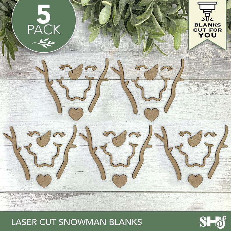 May include: A 5-pack of laser-cut wooden snowman face components, including carrot-shaped noses, curved mouths, heart-shaped buttons, and branch-like arms. The text "5 PACK" and "BLANKS CUT FOR YOU" appears in the corners of the image.