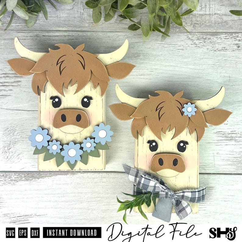 Pu&ograve; includere: Due sagome in legno di mucche highland con volti color crema, capelli marroni e corna. Una mucca presenta una ghirlanda di fiori blu, mentre l'altra indossa un fiocco a quadri bianco e nero con una foglia verde e un singolo fiore blu.