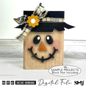 Könnte beinhalten: Eine Vogelscheuchen-Dekoration aus Holz mit einem schwarzen Hut, einem ausgefransten schwarz-weiß karierten Band und einer gelben Blume. Das Gesicht hat zwei schwarze ovale Augen, eine orangefarbene dreieckige Nase und ein schwarzes Lächeln.