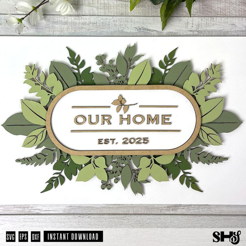 May include: A wooden sign with a leafy green floral design around the perimeter. The sign reads "Our Home Est. 2025".