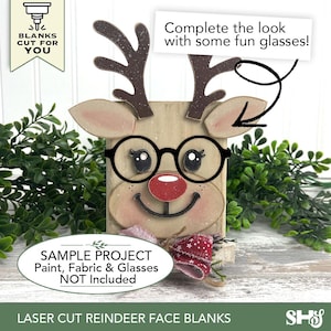May include: A laser-cut wooden reindeer face blank featuring dark brown antlers, a red nose, and black circular glasses. The piece includes text that reads: BLANKS CUT FOR YOU, Complete the look with some fun glasses!, and SAMPLE PROJECT Paint, Fabric & Glasses NOT Included.