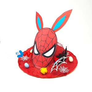 May include: Red and blue bunny ears with a red and black Spider-Man mask attached to a red felt hat. The hat is decorated with white spiderwebs, black and white city skyline, and blue and white Easter eggs.