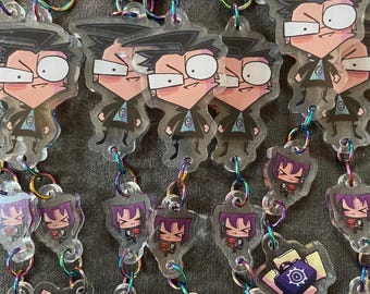 May include: A collection of clear acrylic keychains featuring cartoon characters. The keychains have iridescent clasps and chains. The characters are depicted in various poses and designs, with some holding briefcases. The keychains are on a gray surface.