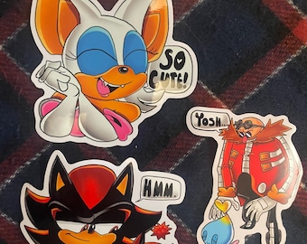 May include: Three cartoon character stickers featuring Rouge the Bat, Shadow the Hedgehog, and Dr. Eggman. Rouge is winking and sticking her tongue out with a speech bubble that says "So Cute!" Shadow is holding a small Shadow the Hedgehog with a speech bubble that says "Hmm." Dr. Eggman is holding a small Chao with a speech bubble that says "Yosh..."