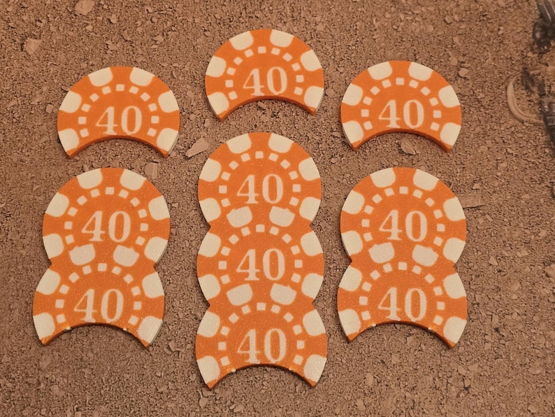 May include: Six orange and white plastic chips with the number "40" printed on them. The chips are shaped like half circles and are arranged in a semi-circle pattern.