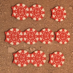 May include: Nine red poker chips with white lettering, each chip has the number "25" printed on it.