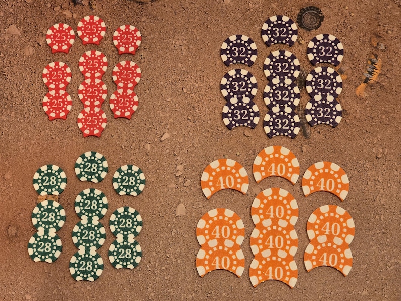 May include: A collection of 10 round chips with different numbers printed on them. The chips are arranged in three groups of three, with one group of four. The chips are red, green, orange, and purple.