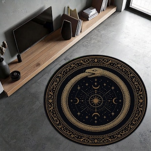 Puede incluir: Una alfombra redonda negra con un diseño de ouroboros dorado, una serpiente que se muerde la cola, y símbolos celestiales. La alfombra tiene un borde detallado y está colocada sobre un suelo de hormigón gris.