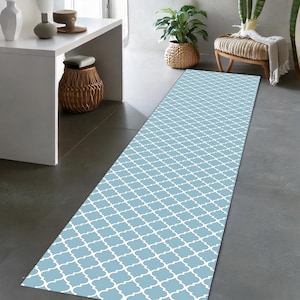 May include: A light blue and white patterned runner rug with a geometric design. The rug is laid out on a gray tiled floor.