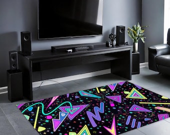 May include: A black and white rug with a geometric pattern in neon pink, blue, green, and yellow. The rug is in front of a black entertainment center with a TV and speakers.