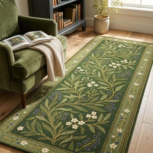 Op de afbeelding: Een rechthoekig vloerkleed met een diepgroene achtergrond en een herhalend botanisch patroon van lichtgroene bladeren, witte bloemen met vijf bloemblaadjes en trossen kleine blauwe bessen, omlijst door een decoratieve rand met bijpassende bloemmotieven.