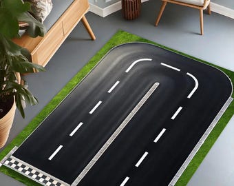 May include: A black and white race track rug with green grass borders. The rug features a checkered finish line and white lines on the black asphalt.