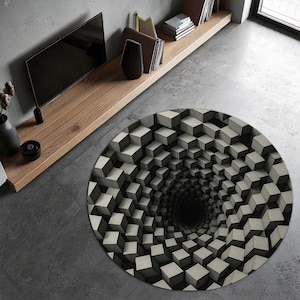 Peut inclure: Un tapis rond avec un motif de cubes 3D en nuances de gris et de noir, créant une illusion visuelle de tunnel. Le motif du tapis donne une impression de profondeur et de mouvement, adapté à un espace de vie moderne.