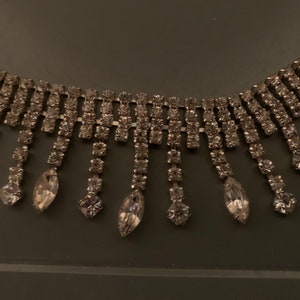 K&ouml;nnte beinhalten: Eine silberne Strass-Choker-Kette mit einer Fransen aus herabh&auml;ngenden Strasssteinen.