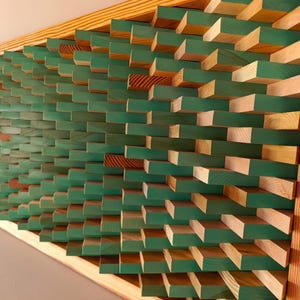 Puede incluir: Obra de arte mural de madera con un diseño geométrico. La obra presenta numerosos bloques rectangulares, principalmente pintados de verde, con detalles de madera natural. La pieza está enmarcada en madera clara. Medidas en centímetros.