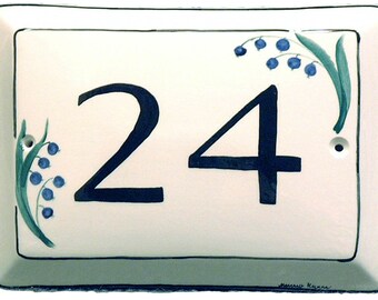 May include: White ceramic house number plaque with black painted numbers "24" and blue and green painted lily of the valley flowers.