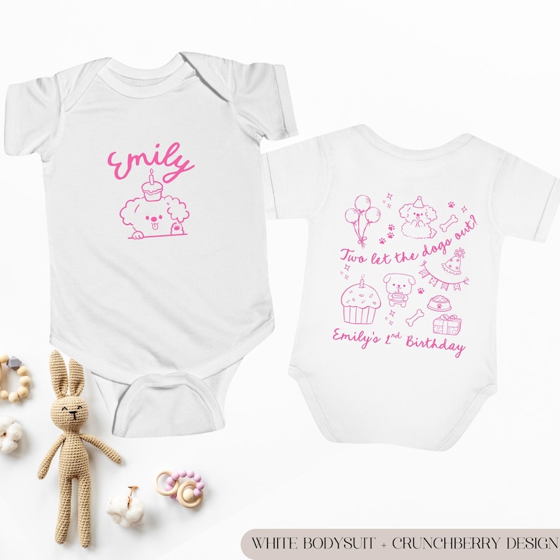 May include: Two white baby bodysuits with pink graphics. One features the name "Emily" and a dog with a cupcake. The other says "Two let the dogs out?" and "Emily's 1st Birthday" with dog-themed illustrations.