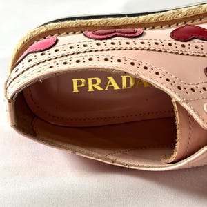 Interior view looking down into the pink leather shoe, revealing the gold stamped Prada logo on the insole.