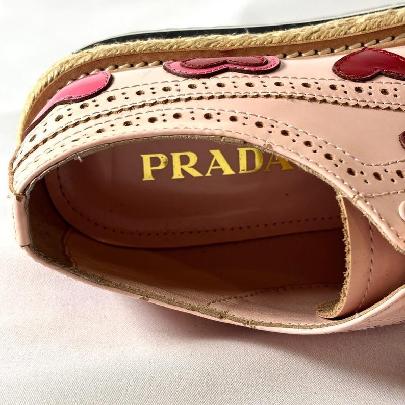 Interior view looking down into the pink leather shoe, revealing the gold stamped Prada logo on the insole.