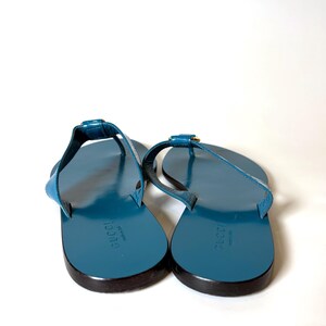 Rear view of the blue flat leather sandals displaying the Gucci logo stamped on the insoles.