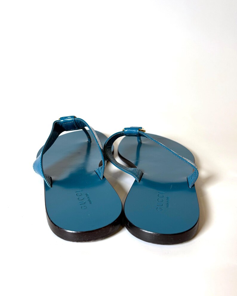 Rear view of the blue flat leather sandals displaying the Gucci logo stamped on the insoles.