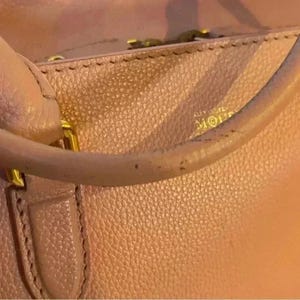 A close-up of the top edge of a pink leather bag, showing a handle attachment and the embossed text "ALEXANDER MCQUEEN" on the bag's surface.