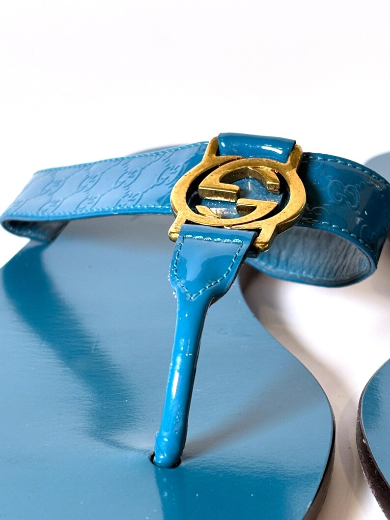 Close-up of the blue patent leather strap and gold-tone interlocking G hardware on the sandal.
