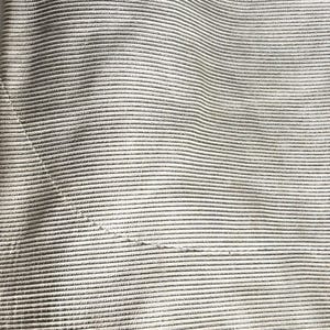 Macro shot of the horizontal ribbed texture on the cream leather skirt fabric.