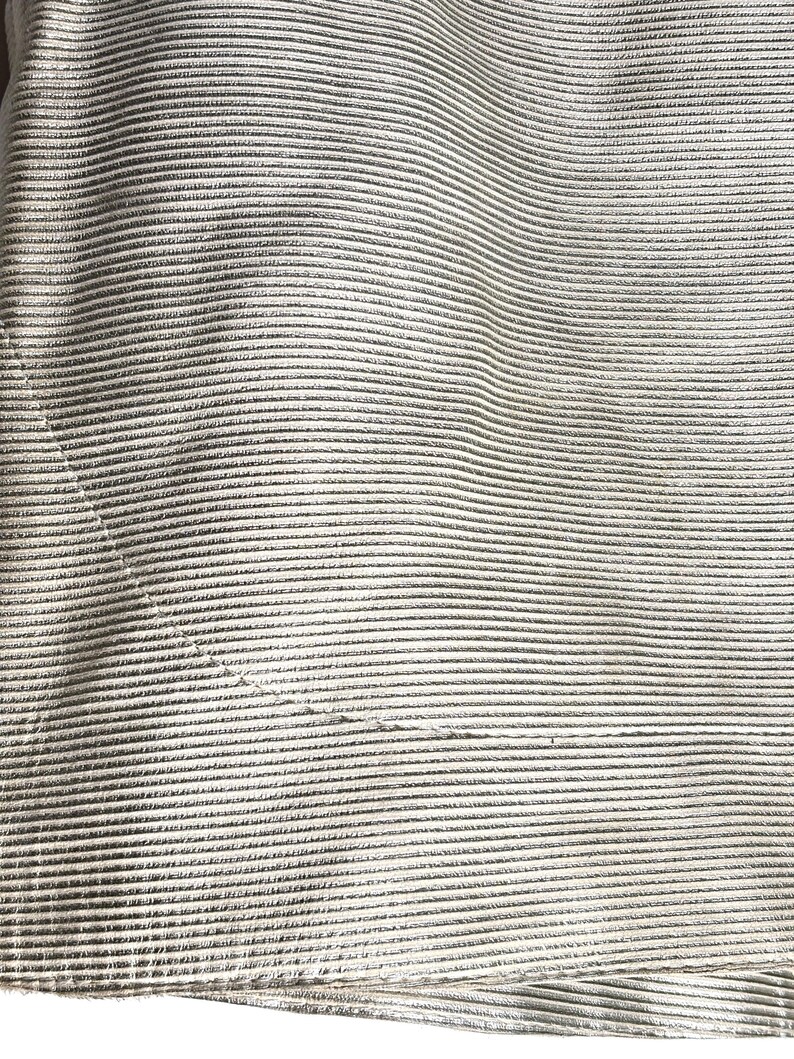 Macro shot of the horizontal ribbed texture on the cream leather skirt fabric.