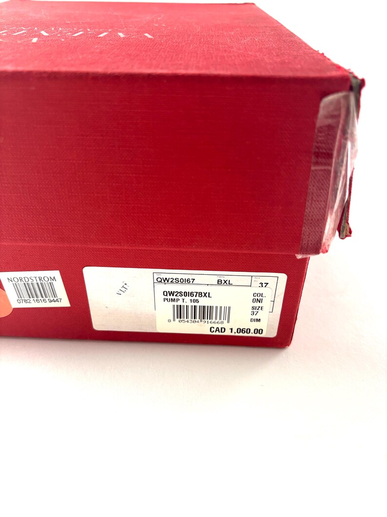May include: A red shoe box with a white label displaying product information. The label includes the style number, size 37, and other details. The box is sealed with clear tape.