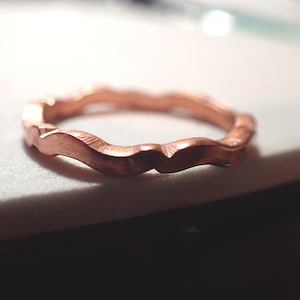 May include: A copper ring with a wavy, textured design.