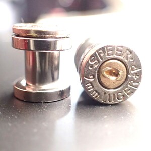 May include: Two silver bullet earrings, one with a silver post and the other with a 9mm Speer Luger bullet.