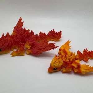 May include: Two fire dragon figurines, one larger than the other, are made of red and orange plastic. The dragons have a flame-like design and are posed in a flying position.