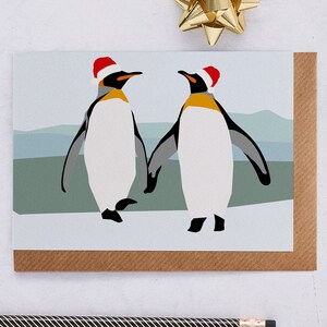 Carte de pingouins de Noël, avec des chapeaux de Père Noël se tenant la main