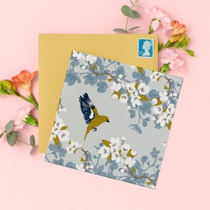Greenfinch card, greenfinch against a pale blue sky and apple blossom