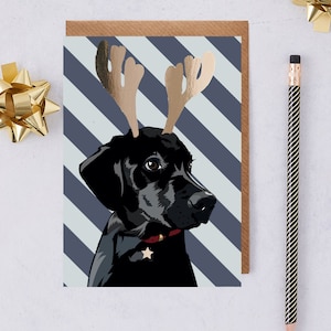 Imbullonare la cartolina di Natale del labrador nero con la sua fascia per corna di renna in lamina d'oro