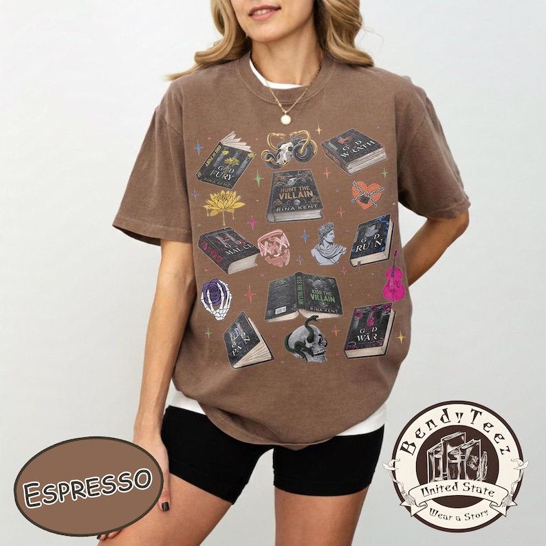 May include: Espresso-colored t-shirt featuring a collection of illustrated books, skulls, and floral accents. The shirt has a relaxed fit and a crew neck. The text "HUNT THE VILLAIN" is visible on one of the books. The shirt is from Bendy Tee.