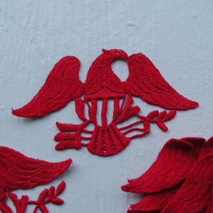 May include: A set of red felt appliques in the shape of an eagle with an American flag design. The appliques are perfect for adding a patriotic touch to crafts and projects.