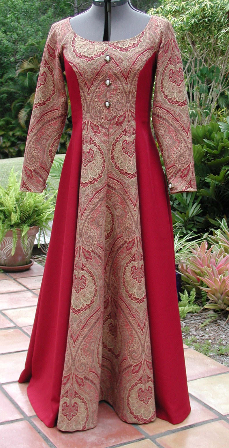 May include: A long red dress with a paisley pattern in gold and red. The dress has a scoop neck and long sleeves. The dress is made of a soft, flowing fabric.