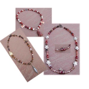 May include: Three necklaces featuring various beads. One necklace has red and white beads with turtle charms. Another has brown, tan, and clear beads with a leaf-shaped pendant. The third has red and silver beads with flower and frog charms.