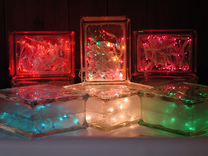 May include: Five rectangular glass blocks arranged in two rows, each containing strings of glowing LED lights. The top row features red and multi-colored lights, while the bottom row displays blue, warm white, and green lights inside the clear glass.