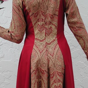 May include: A red dress with a paisley pattern in gold and red. The dress has a fitted bodice and a flowing skirt.