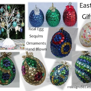 Op de afbeelding: Paaseieren ornamenten gemaakt van echte eieren, bedekt met kleurrijke pailletten. De ornamenten zijn handgeblazen en verkrijgbaar in verschillende kleuren, waaronder blauw, groen, rood en wit. De tekst "Real Egg Sequins Ornaments Hand Blown" staat op de afbeelding.