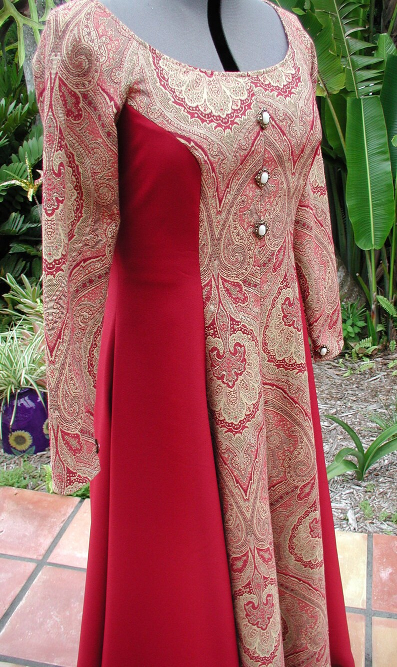 May include: A red and gold paisley patterned dress with a fitted bodice and a flowing skirt. The dress has a scoop neckline and three white buttons down the front.