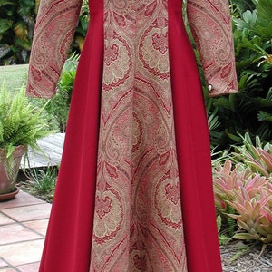 May include: A long-sleeved red dress with a paisley pattern in gold and red. The dress has a scoop neckline and a fitted bodice. The skirt is full and flowing.