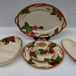 May include: A set of five vintage ceramic dishes with a brown and green apple design. The set includes a large oval serving platter, two oval dishes, a small oval dish with a divider, and a creamer.