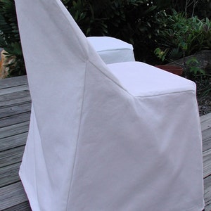 May include: White chair cover with a simple design. The cover is made of a smooth, white fabric and has a fitted back and seat.