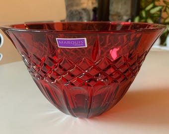 Op de afbeelding: Een robijnrode Marquis by Waterford kristallen kom. De kom heeft een diamantgeslepen patroon aan de zijkanten en een gladde, uitlopende rand. Een klein label met de merknaam is zichtbaar. Geschikt voor serveren of decoratie.